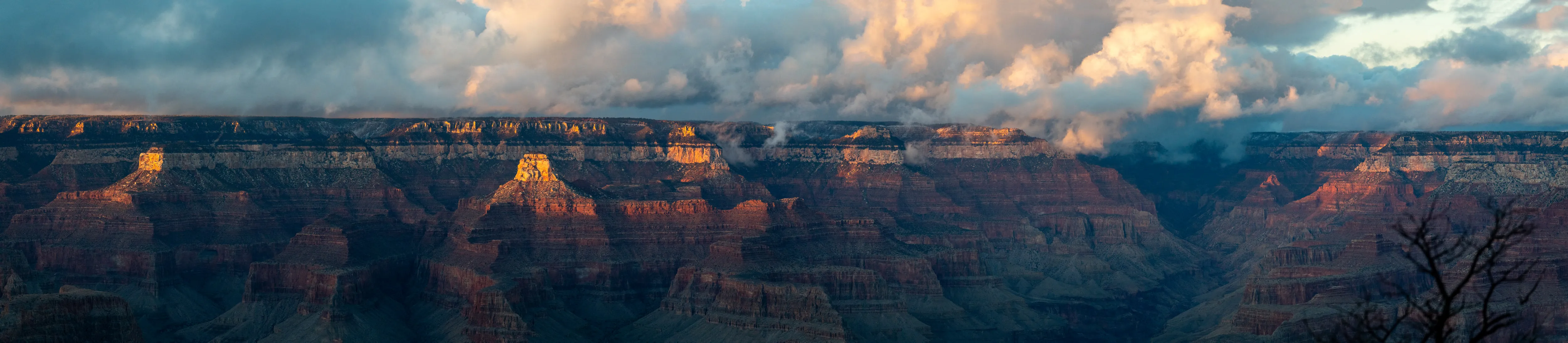 A long panorama of canyon walls and buttes under late clouds.