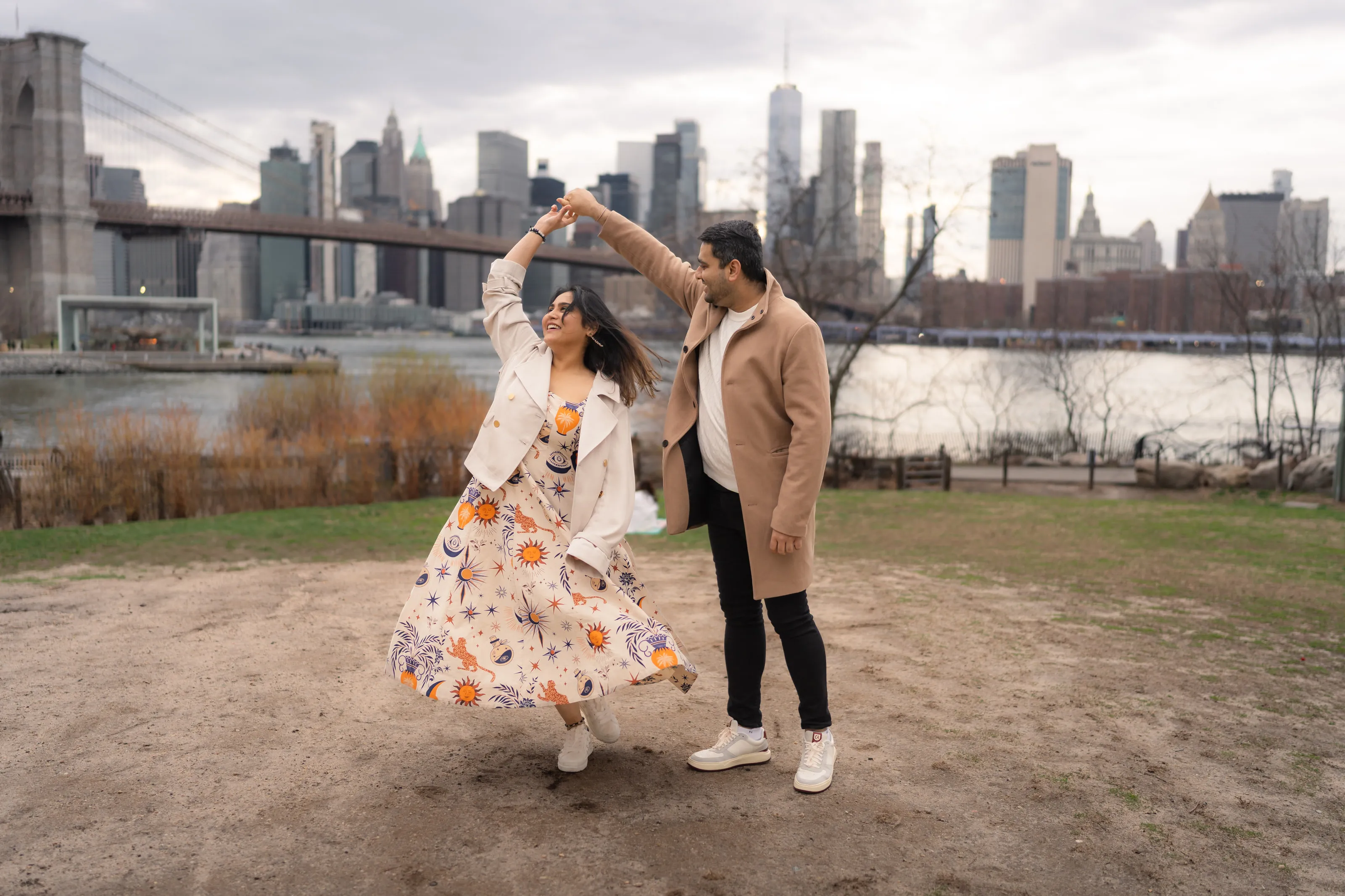 The couple dance by the river, with the Brooklyn Bridge and the Manhattan skyline behind them.